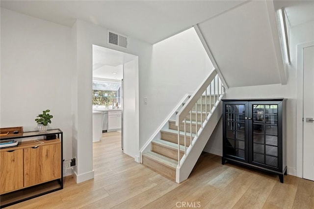 stairway featuring wood finished floors, visible vents, and baseboards