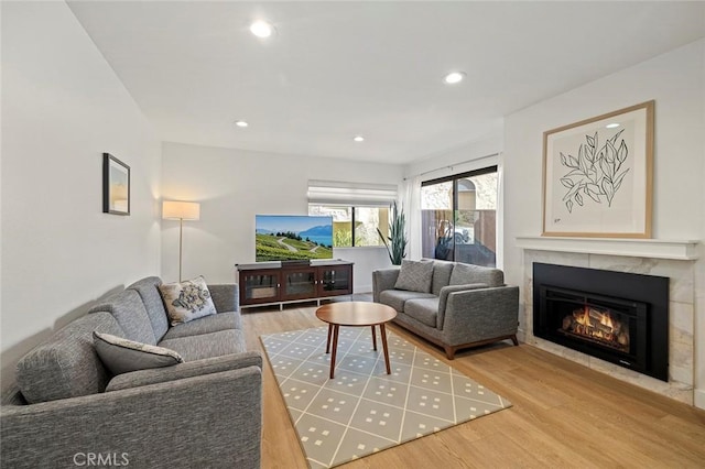 living room featuring a tile fireplace, recessed lighting, and wood finished floors