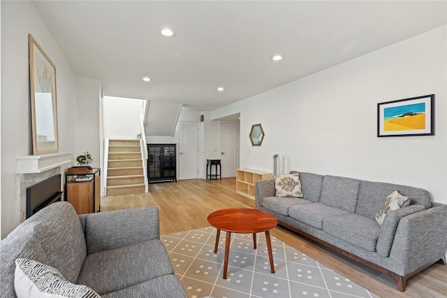 living area with light wood-style floors, recessed lighting, stairs, and a high end fireplace