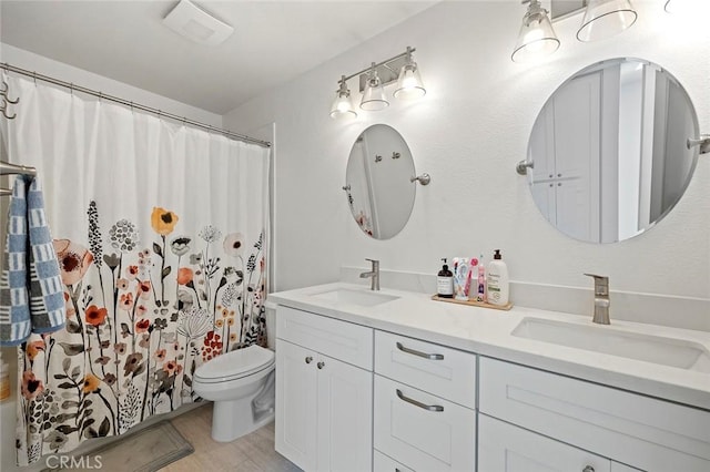 bathroom with double vanity, wood finished floors, a sink, and toilet