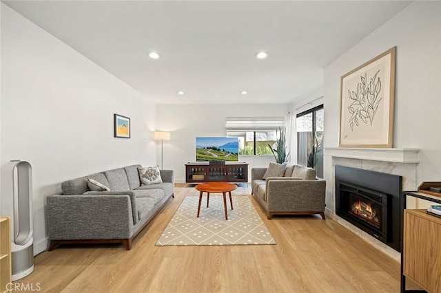 living room featuring light wood-type flooring, a glass covered fireplace, baseboards, and recessed lighting