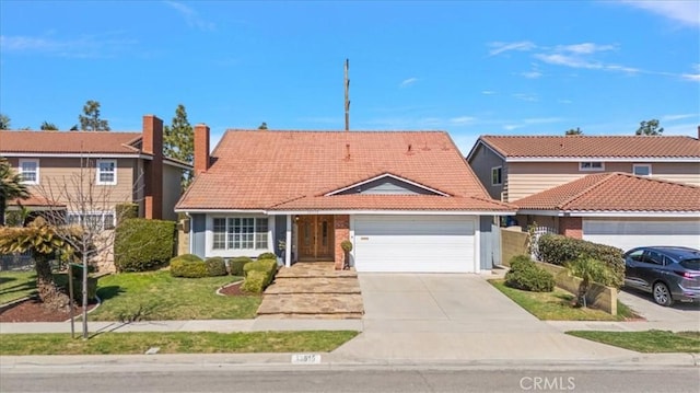 traditional-style house with a front lawn, concrete driveway, an attached garage, and a tiled roof