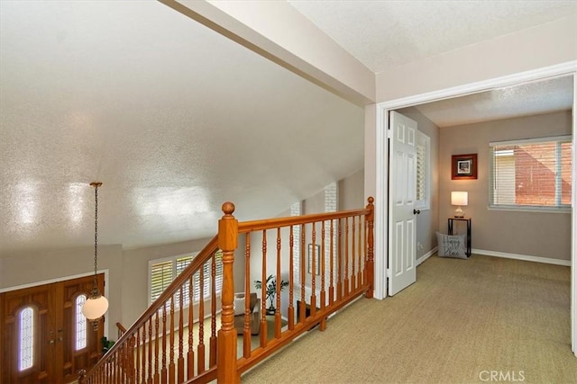 hall with carpet floors, a textured ceiling, and baseboards