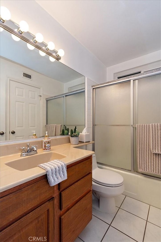 full bath with visible vents, toilet, combined bath / shower with glass door, vanity, and tile patterned floors