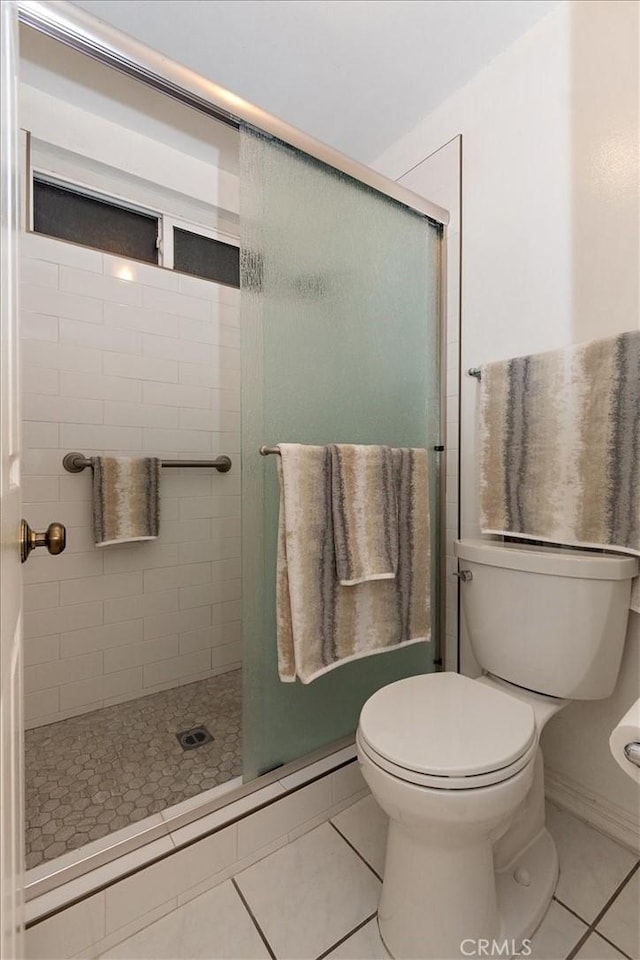 full bathroom with a stall shower, toilet, and tile patterned floors