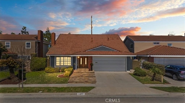 view of front of home featuring a garage, concrete driveway, a lawn, and a tiled roof