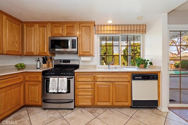 kitchen featuring light countertops, appliances with stainless steel finishes, a sink, and brown cabinets