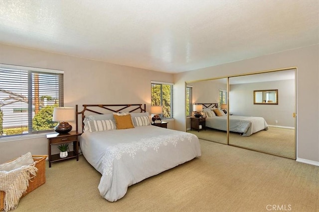 carpeted bedroom with a closet and baseboards