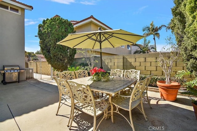 view of patio with outdoor dining area, fence, and area for grilling