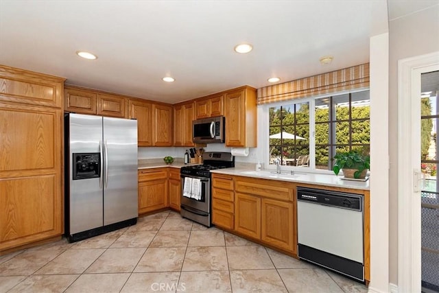 kitchen with light tile patterned floors, recessed lighting, light countertops, appliances with stainless steel finishes, and a sink