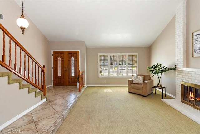 carpeted entryway with a fireplace, visible vents, baseboards, vaulted ceiling, and stairway