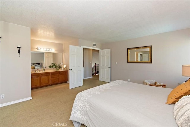 bedroom with light carpet, connected bathroom, visible vents, and baseboards