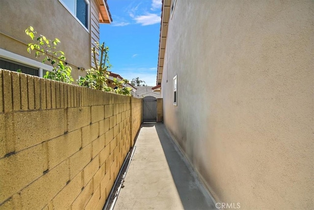 view of side of property featuring a gate, fence, and stucco siding