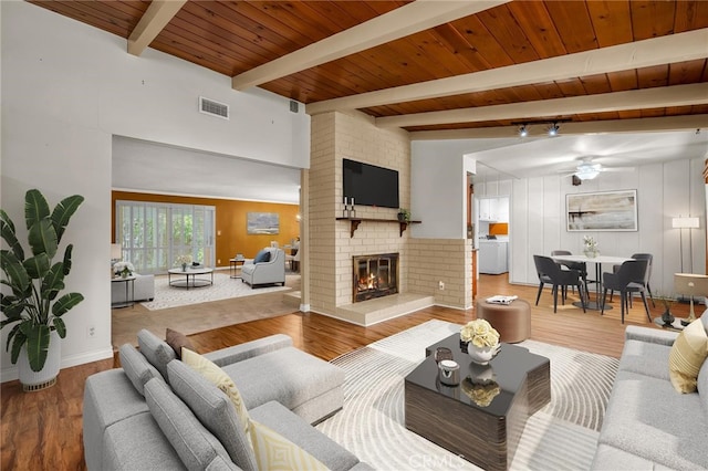 living room with washer / dryer, a brick fireplace, wood finished floors, and visible vents