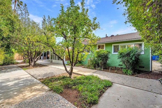 view of front facade featuring driveway, crawl space, fence, and stucco siding