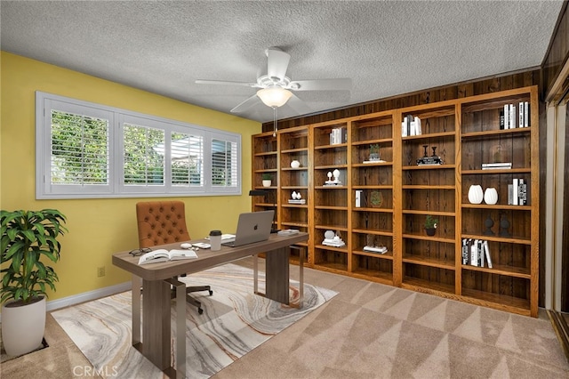 office with ceiling fan, a textured ceiling, baseboards, and light colored carpet