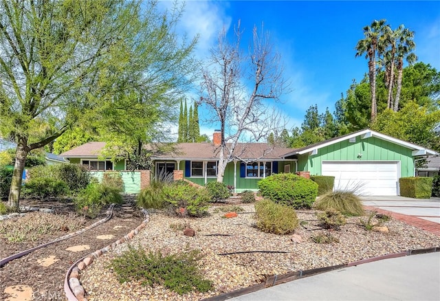 ranch-style house with driveway, a chimney, and an attached garage