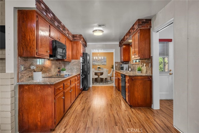 kitchen with black appliances, light wood-style flooring, visible vents, and backsplash