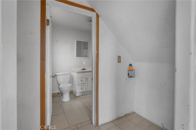 bathroom featuring tile patterned flooring, vaulted ceiling, vanity, and toilet