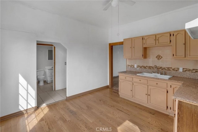 kitchen with ceiling fan, a sink, light wood-style floors, light countertops, and tasteful backsplash