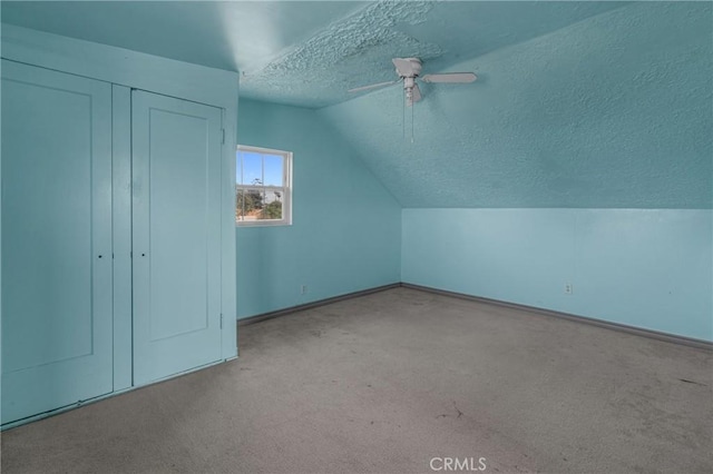 additional living space featuring a ceiling fan, lofted ceiling, carpet flooring, and a textured ceiling