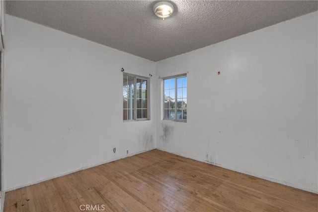 spare room with a textured ceiling and hardwood / wood-style floors