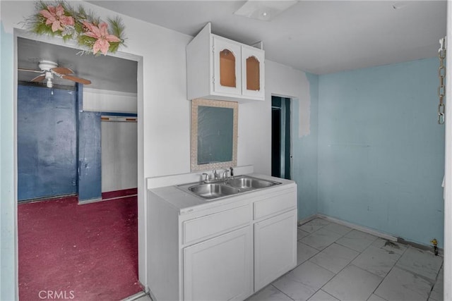 kitchen featuring marble finish floor, light countertops, white cabinets, a sink, and ceiling fan