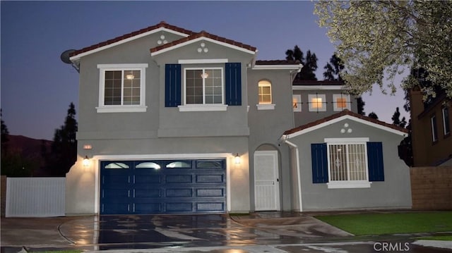 mediterranean / spanish home with a garage, concrete driveway, a tiled roof, fence, and stucco siding