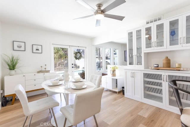 dining area featuring french doors, visible vents, ceiling fan, and light wood-style flooring