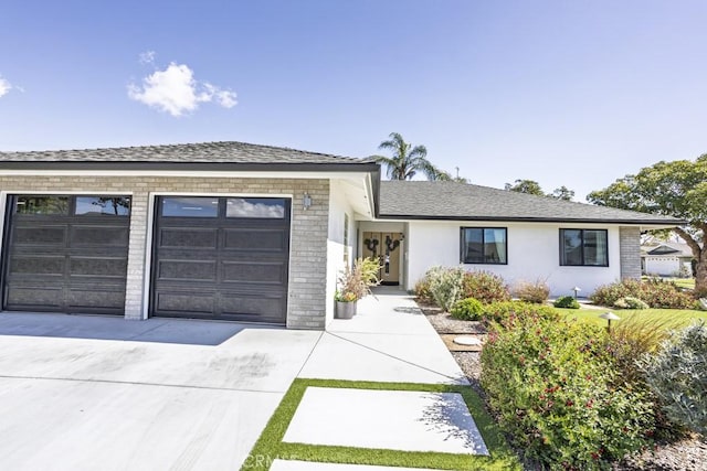 ranch-style home with roof with shingles, brick siding, stucco siding, a garage, and driveway