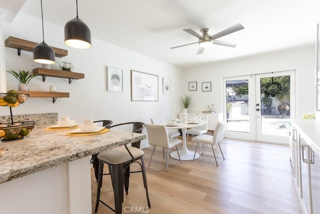 dining space with ceiling fan, french doors, and light wood-style flooring