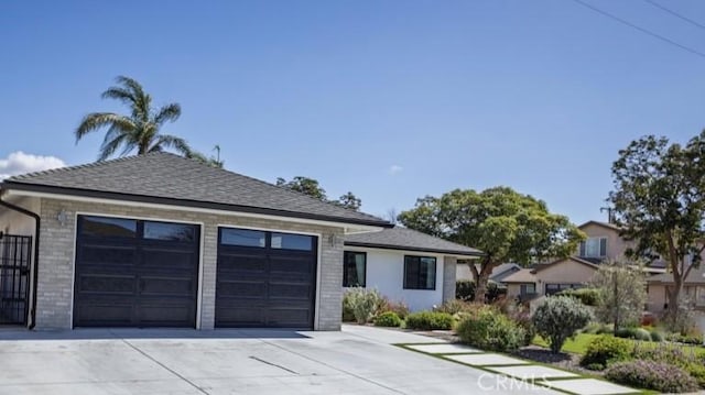 view of front of home with driveway, brick siding, an attached garage, and a shingled roof