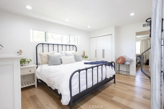 bedroom featuring light wood finished floors, multiple windows, a closet, and visible vents