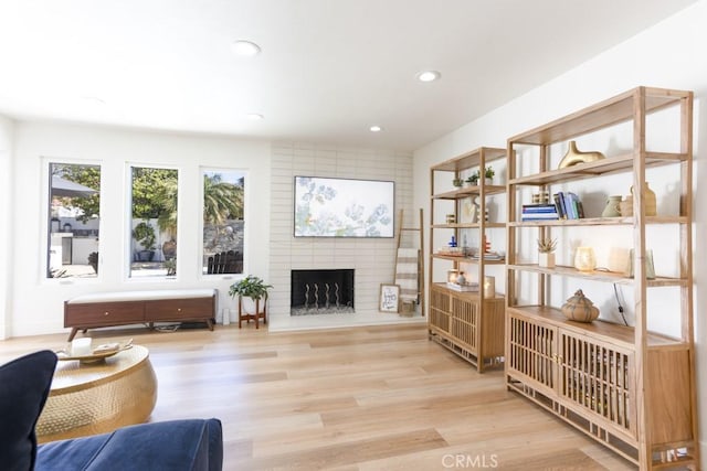 living area featuring a brick fireplace, wood finished floors, and recessed lighting