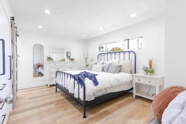 bedroom featuring baseboards, a barn door, recessed lighting, and light wood-style floors