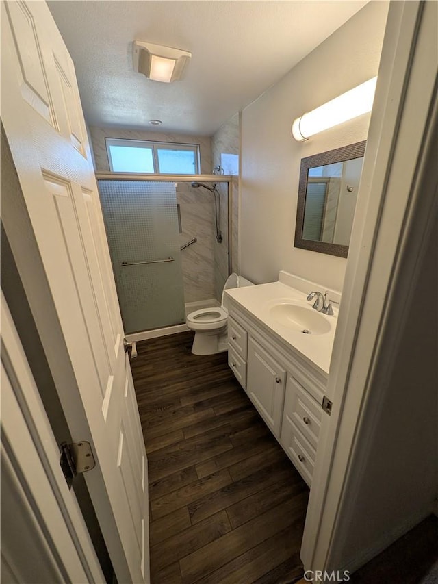 bathroom featuring vanity, a shower stall, toilet, and wood finished floors