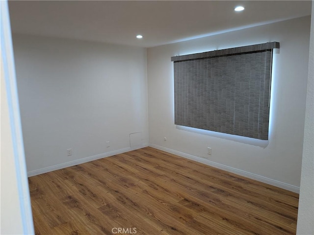 spare room with recessed lighting, baseboards, and wood finished floors