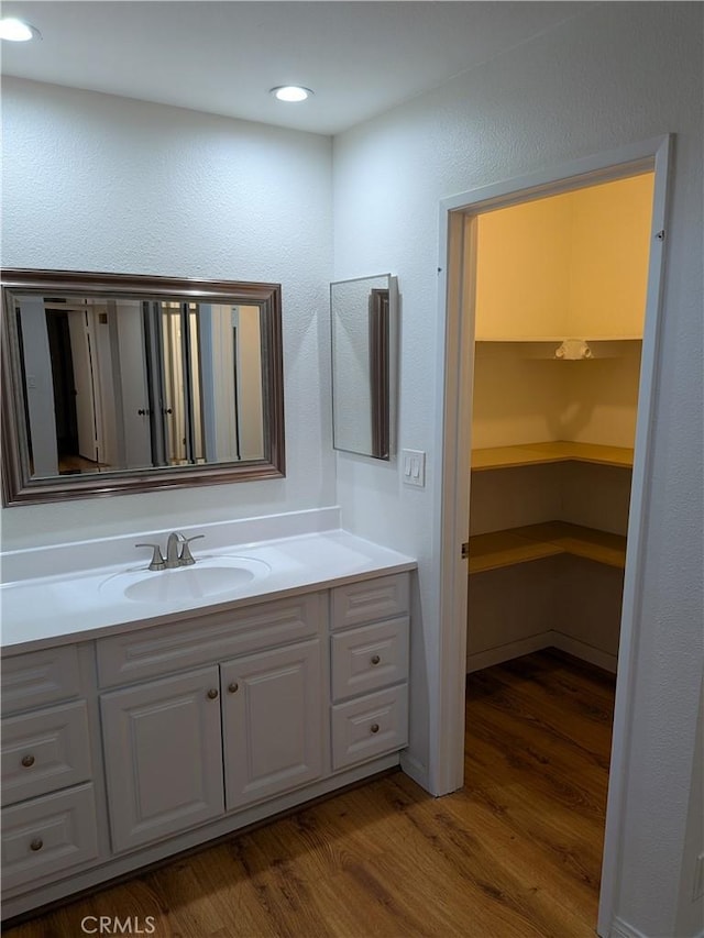 bathroom featuring wood finished floors, vanity, and recessed lighting