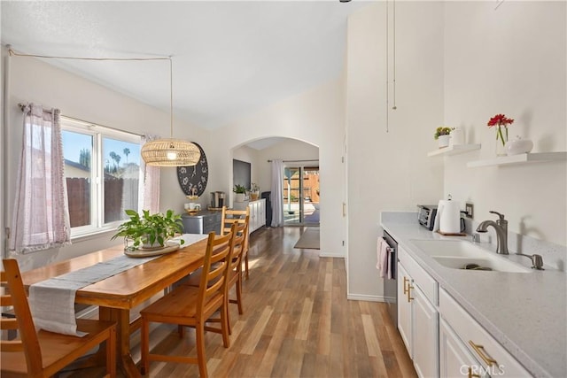 dining space with arched walkways, baseboards, and wood finished floors