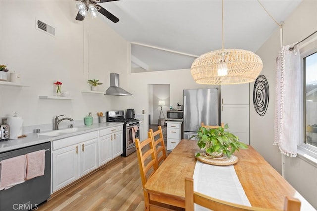 dining area with lofted ceiling, ceiling fan, light wood-type flooring, and visible vents