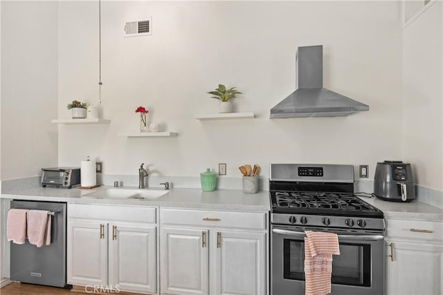 kitchen with appliances with stainless steel finishes, light countertops, a sink, and wall chimney range hood