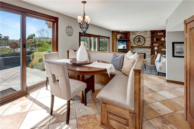 dining space featuring built in shelves, a notable chandelier, and a fireplace