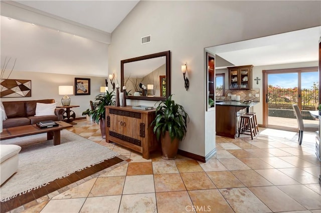 living area featuring high vaulted ceiling, visible vents, baseboards, and light tile patterned floors