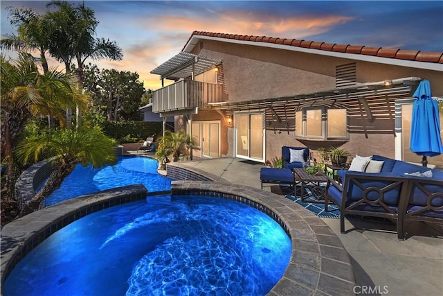 pool at dusk with a pool with connected hot tub and a patio