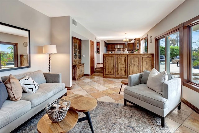 living area with an inviting chandelier, baseboards, light tile patterned floors, and visible vents