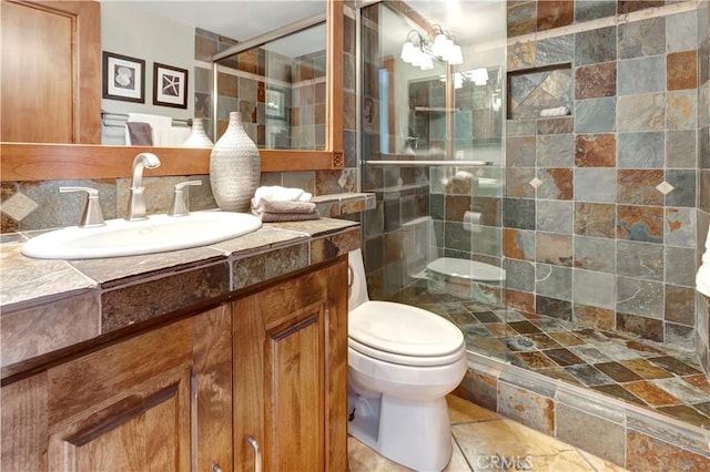 bathroom featuring toilet, a stall shower, backsplash, and vanity