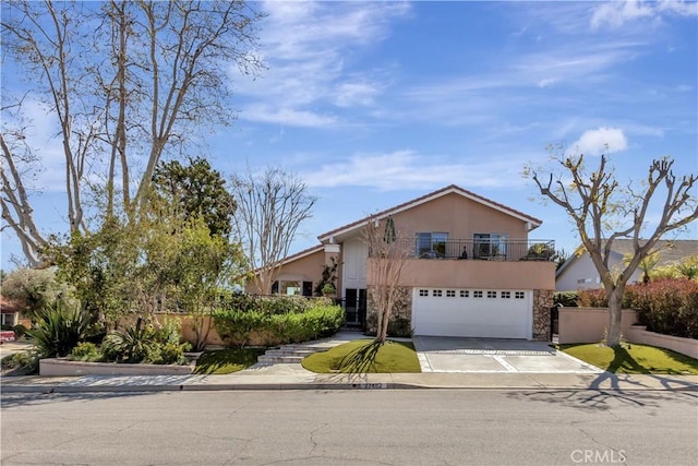 view of front of house with stucco siding, fence, a garage, stone siding, and driveway