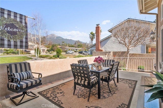 view of patio / terrace featuring outdoor dining area, fence, and a mountain view