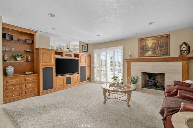 living area with a tile fireplace, light carpet, and a textured ceiling