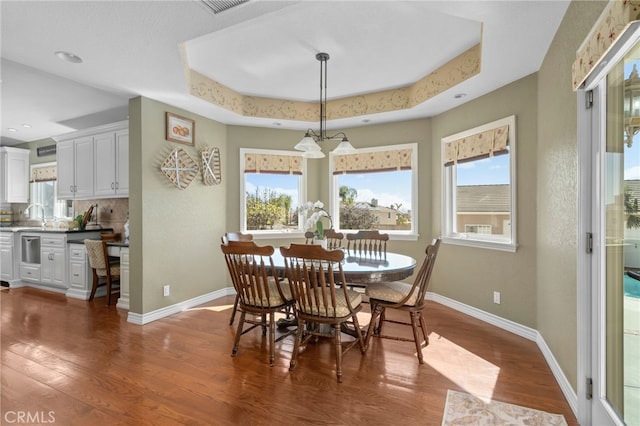 dining area with a tray ceiling, dark wood finished floors, and a wealth of natural light